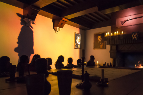 Binnenattractie Hof van Nederland in Madurodam: silhouet op de muur, de open haard brand en bezoekers luisteren aandachtig