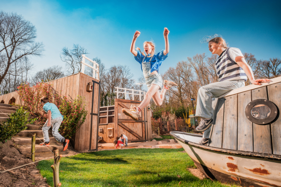 Zomers dagje uit in Madurodam: kinderen klimmen en klauteren in Rivierenland, een meisje maakt een grote sprong