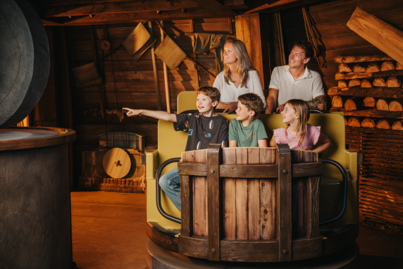 Gezin in binnenattractie De Windjager in Madurodam: zij rijden een oude houtzaagmolen binnen, het jongetje wijst in verwondering