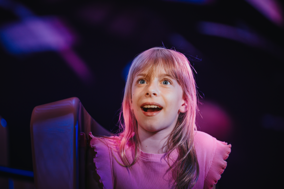 Meisje in binnenattractie De Windjager in Madurodam: zij kijkt met open mond van verbazing om zich heen