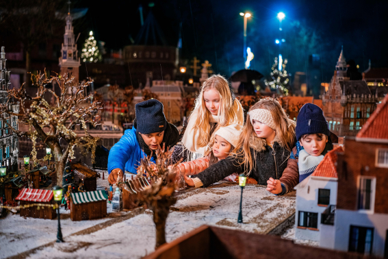 Kids bewonderen winterse miniaturen in Madurodam, sfeervol verlicht en besneeuwd